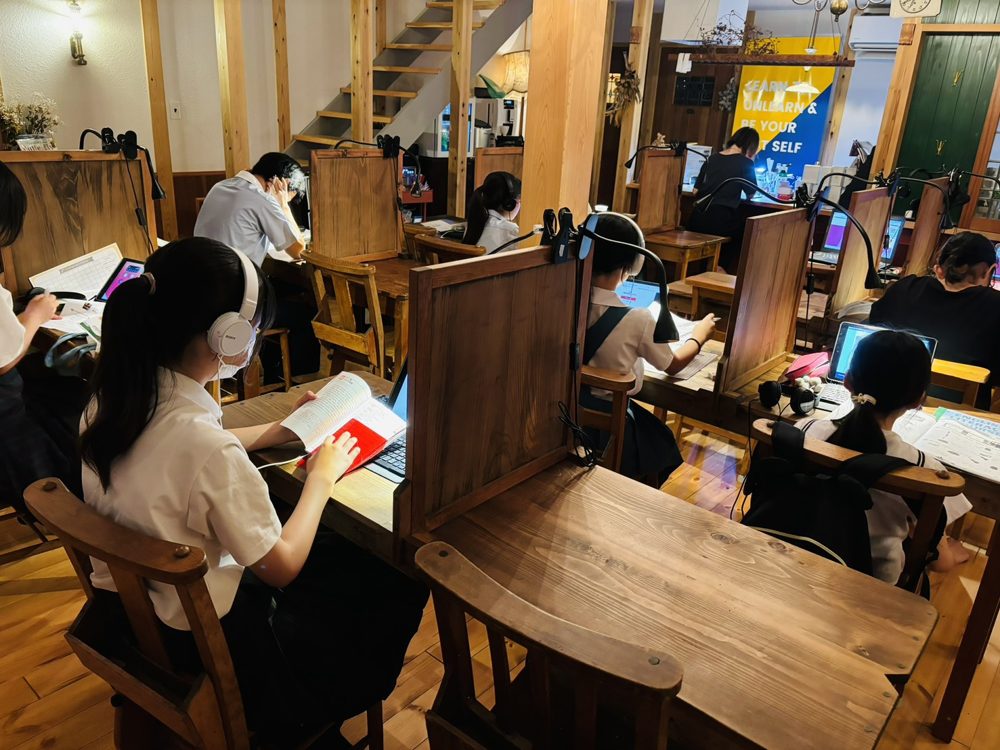 wokwokの教室で、ヘッドホンをつけてテキストとパソコンで学ぶ生徒たち